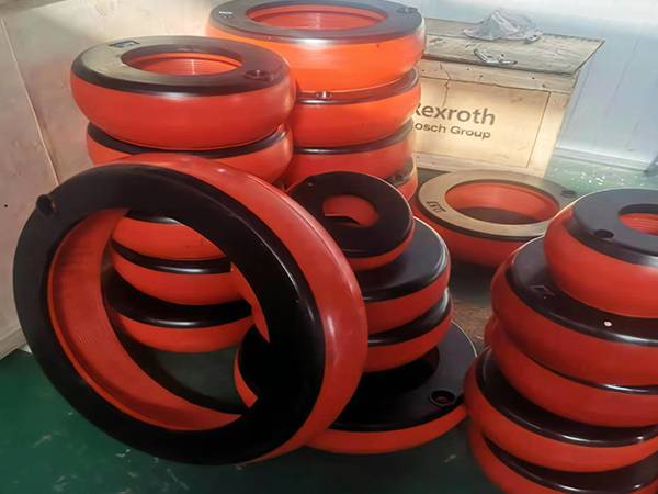 Side view of several piles of orange integral inflatable thread protectors in factory