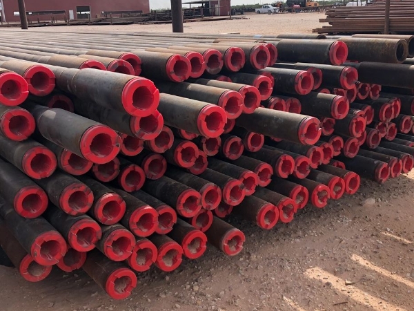 Many casing pipes with thread protectors on the ground